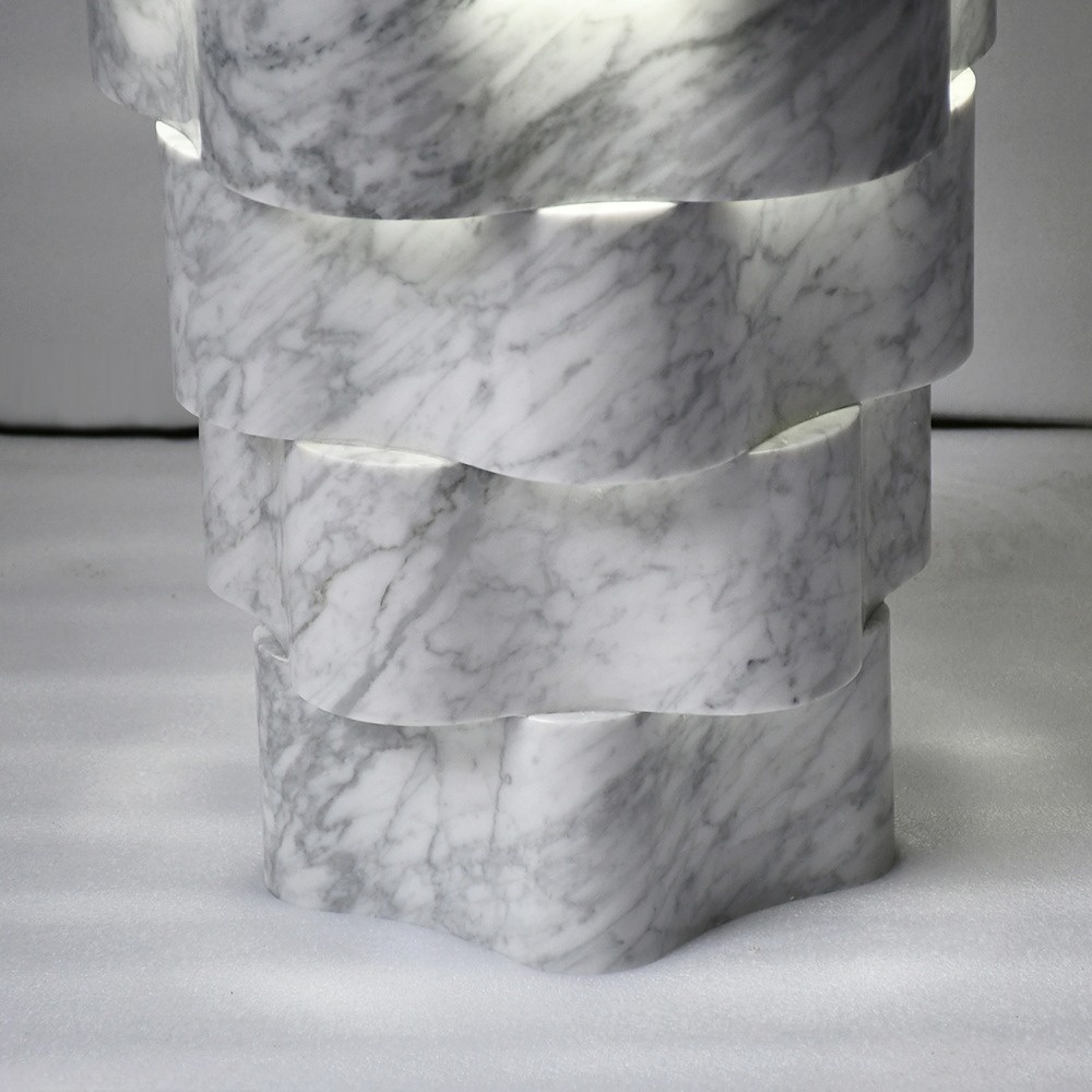 Side view of Carrara marble pedestal sink - layered scalloped tiers and glowing light gaps