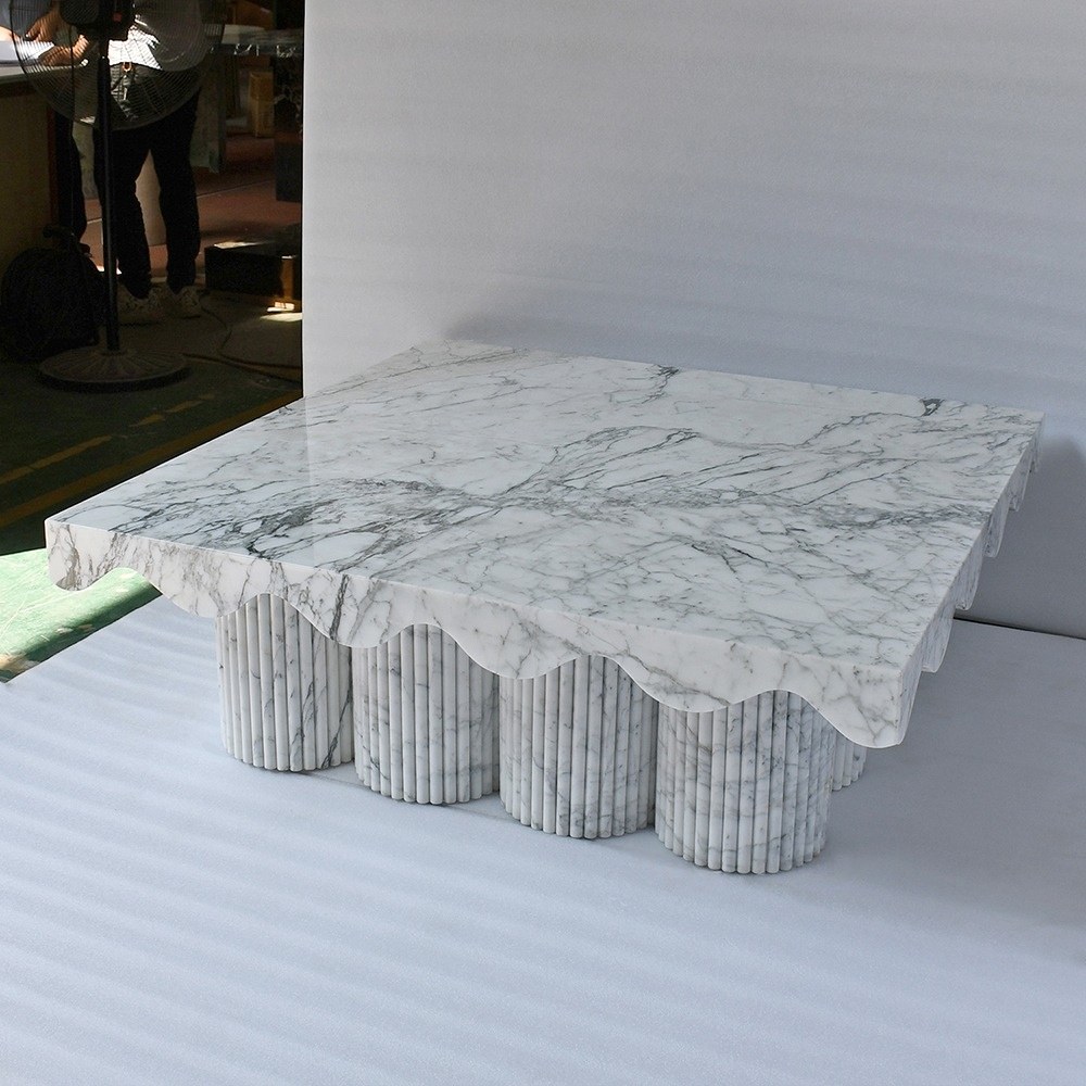 Square white marble coffee table with wavy scalloped edge and ribbed legs
